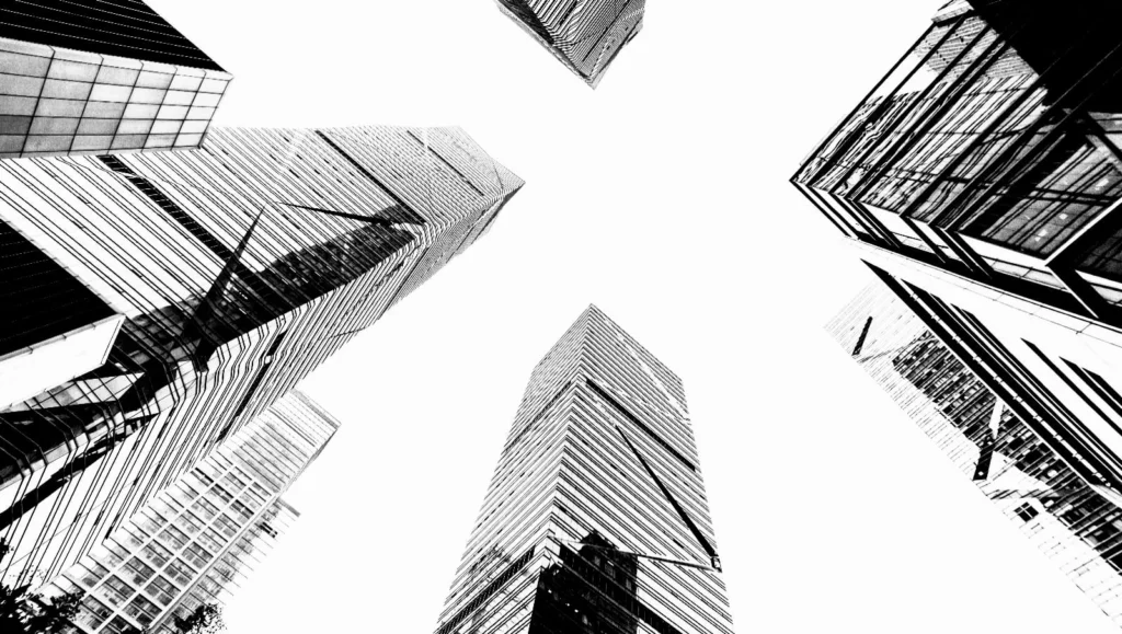 Vista en blanco y negro de rascacielos corporativos desde abajo, representando complejidad, escala y toma de decisiones estratégicas en organizaciones